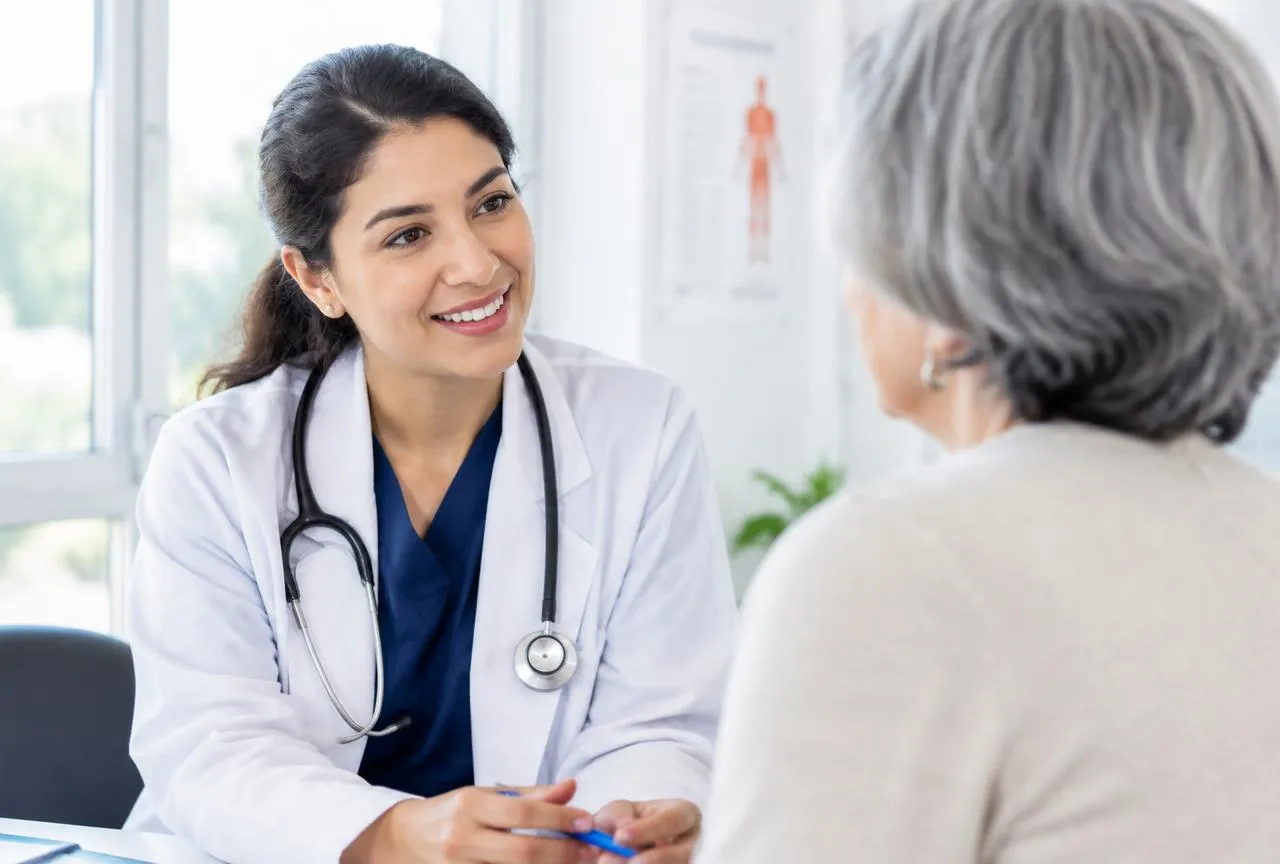 Médica conversando com paciente em consultório, atendimento coberto por plano de saúde